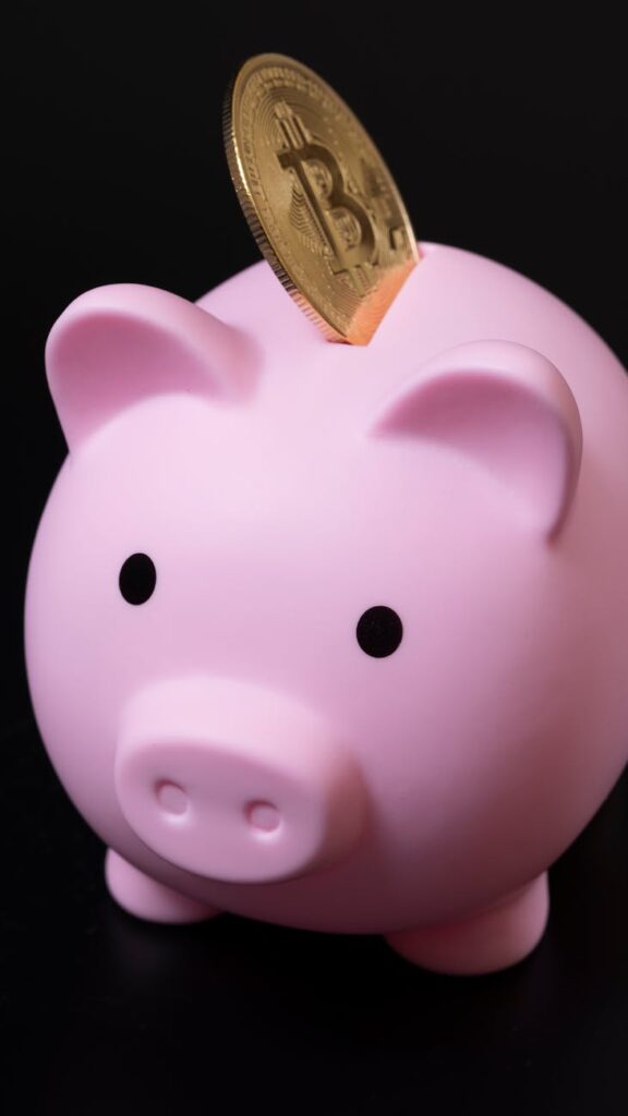 A close-up of a physical Bitcoin coin being dropped into a piggy bank, symbolizing long-term crypto savings for retirement.