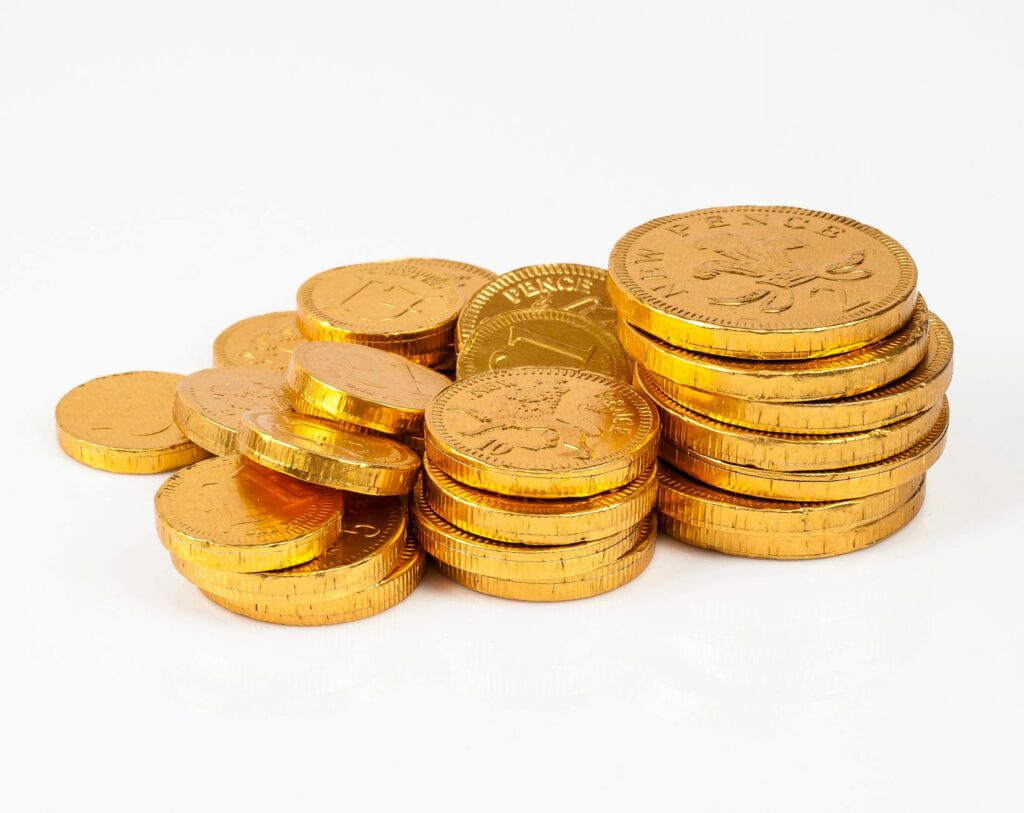 A neat stack of identical, shiny gold coins against a dark background, illustrating the concept of fungibility.