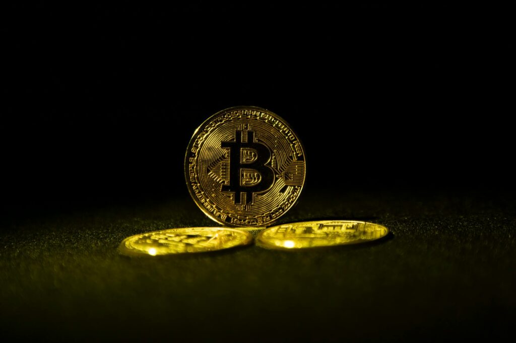 An abstract digital art piece showing a glowing Bitcoin symbol at the center of a global network of interconnected lines.