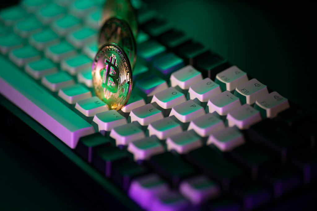 A close-up of a physical Bitcoin coin resting on the keys of a modern laptop keyboard.