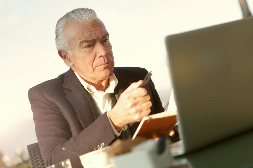 A senior individual carefully reviewing their diverse retirement portfolio including cryptocurrency on a modern laptop.