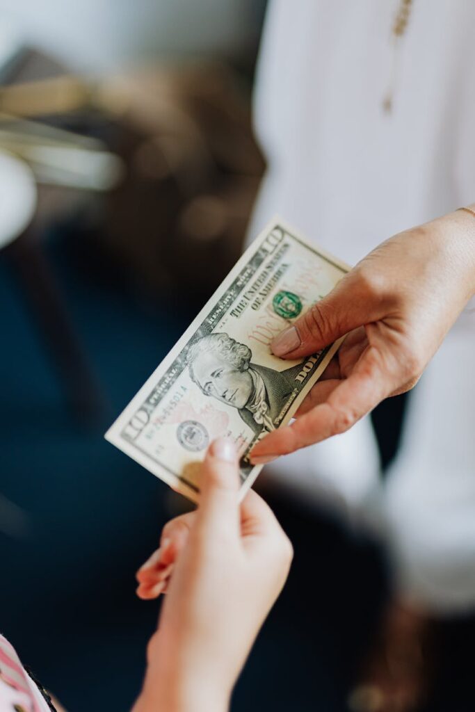 Close-up of two hands, one holding a physical gold Bitcoin and the other holding a stack of cash, symbolizing the conversion of crypto to fiat currency.