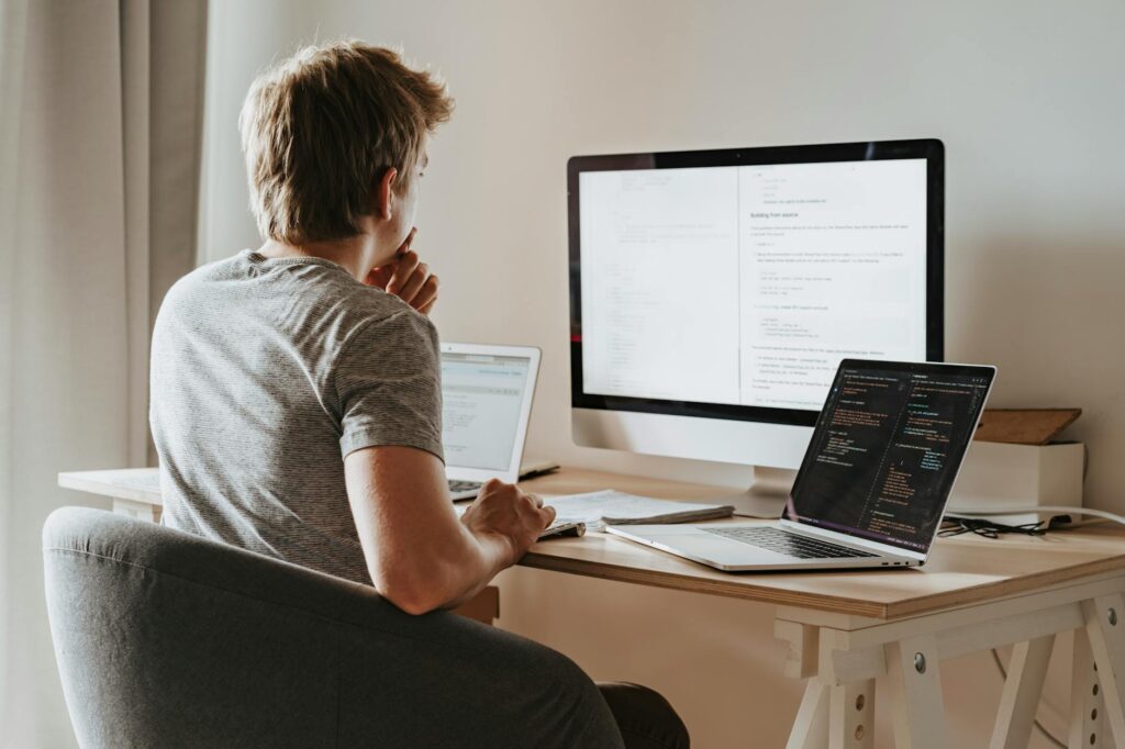 A focused developer typing code on a laptop in a dimly lit room.
