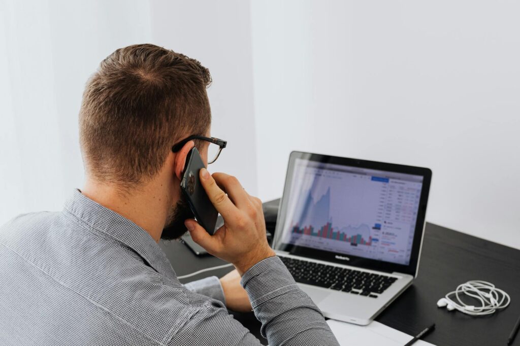 A financial analyst pointing at a complex cryptocurrency candlestick chart on a large monitor in a modern office.