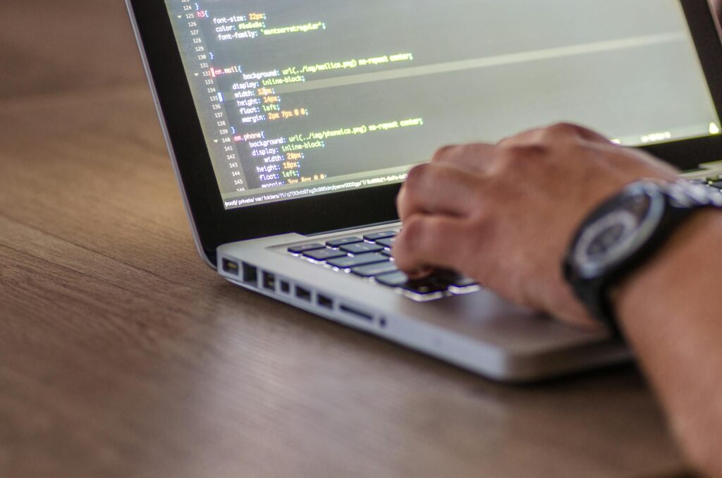 Close-up of a software developer's hands typing code on a laptop with glowing cryptocurrency symbols in the foreground.