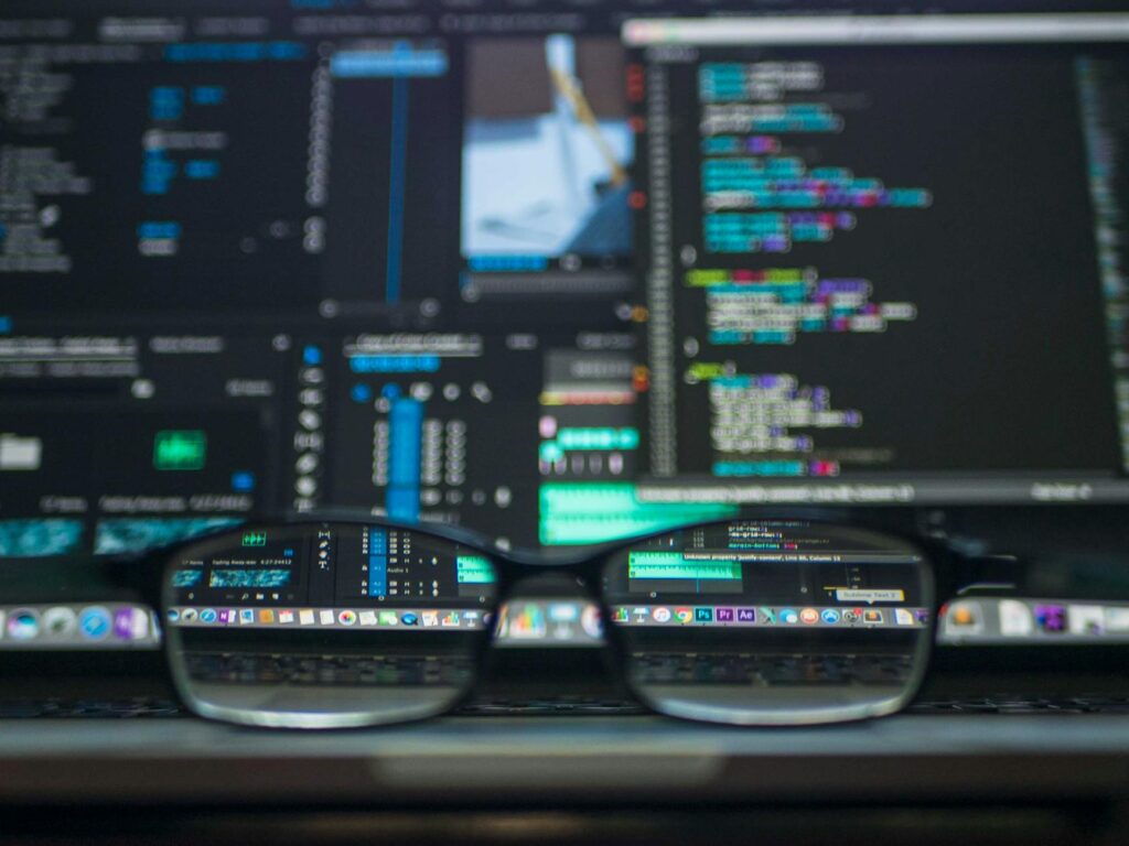A security professional in a dark room analyzing complex code on multiple computer monitors, symbolizing a third-party audit.