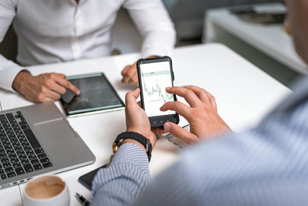 A person's hands holding a smartphone with a cryptocurrency trading app open, showing portfolio values.