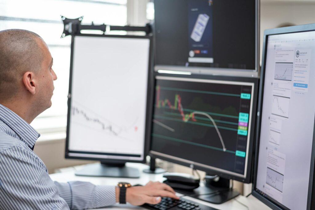 An investor looking concerned while analyzing complex red and green crypto charts on their laptop.