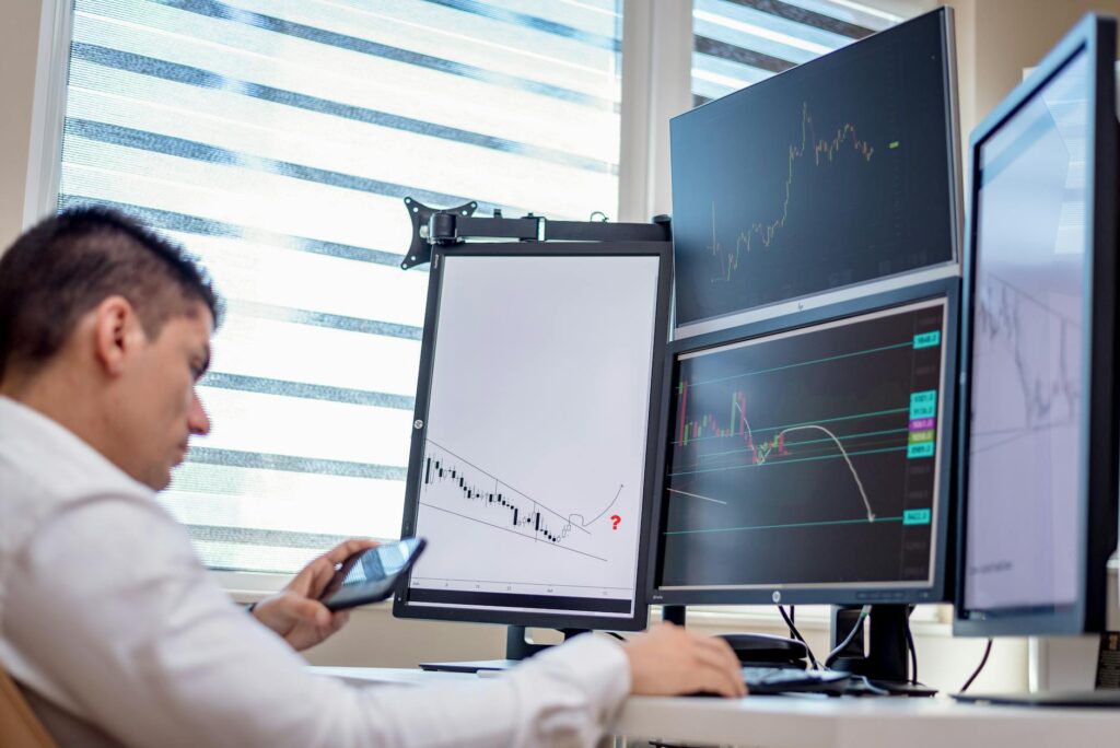 An investor carefully researching cryptocurrency data on multiple monitors.