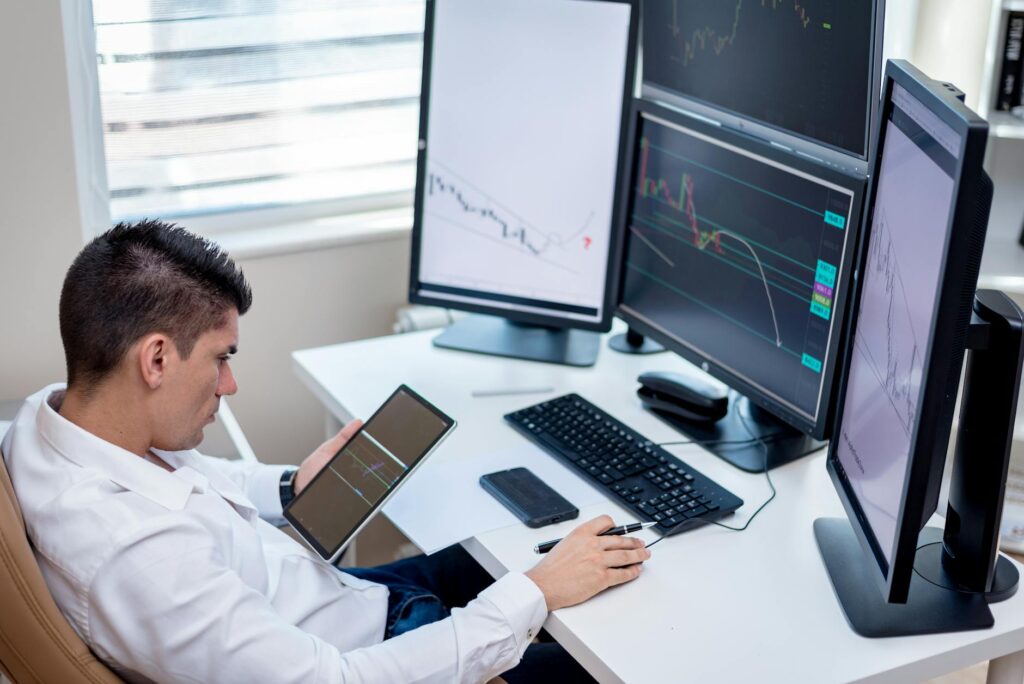 A focused financial trader looking at complex cryptocurrency candlestick charts on several computer screens.