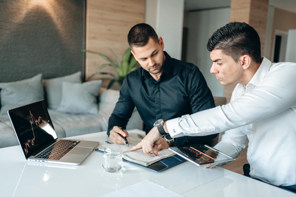 A focused investor pointing at complex cryptocurrency price charts on a modern desktop computer.