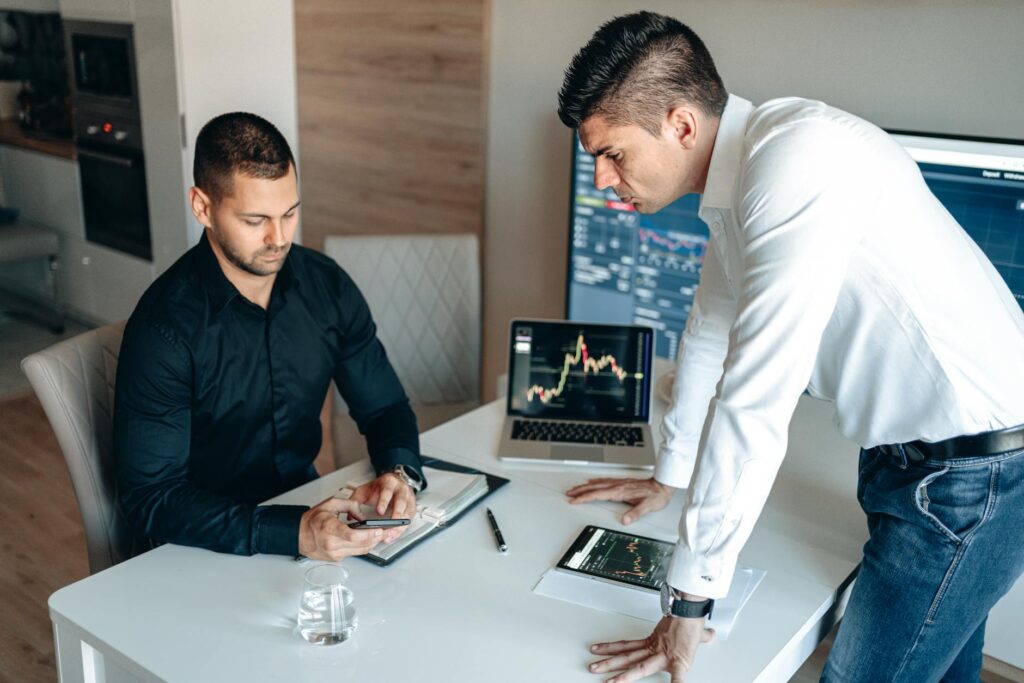 A diverse team of advisors collaborating around a table, pointing at financial crypto charts on a digital tablet.