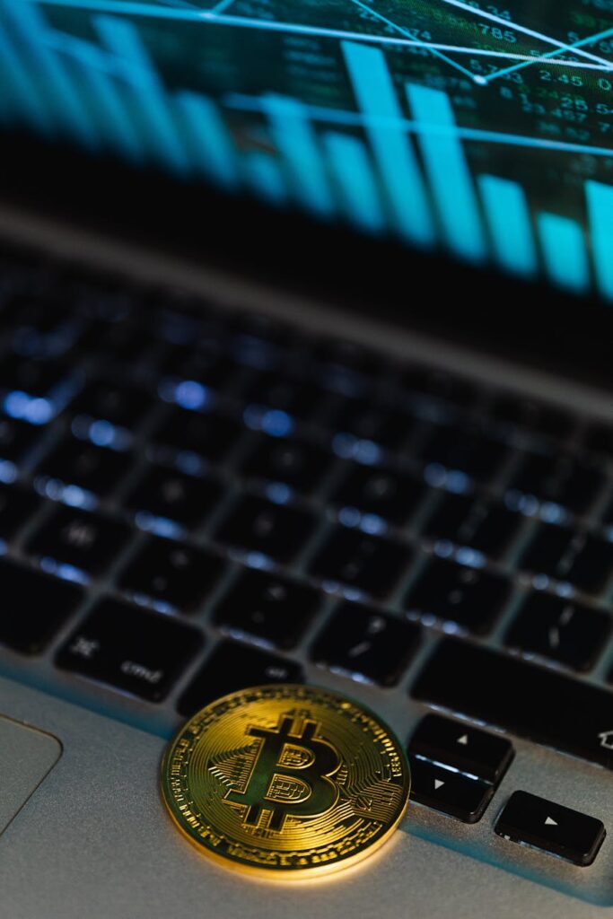 A close-up shot of a golden physical Bitcoin placed on the keys of a laptop, blending the digital and physical.