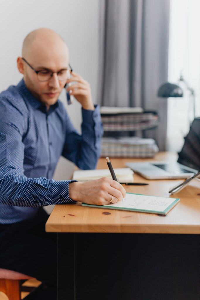 A planning setup for crypto investing with physical bitcoin coins, a notebook, and a pen on a wooden desk.