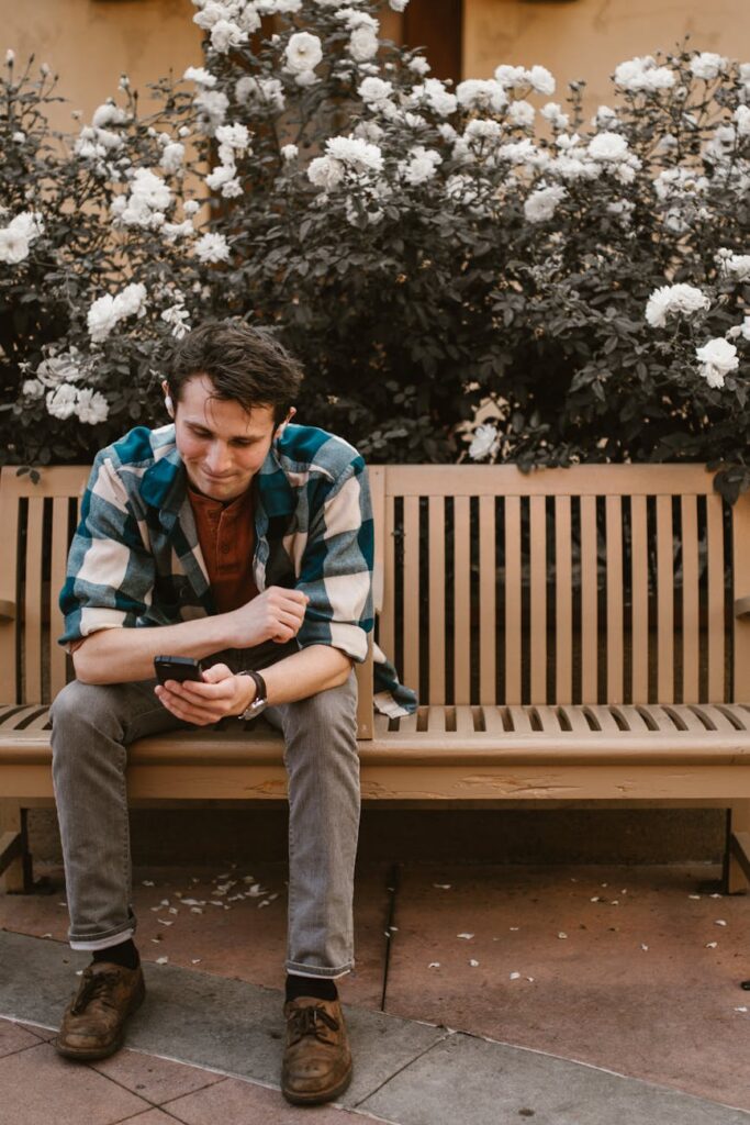 A close-up of a person's hand holding a smartphone displaying a green, upward-trending cryptocurrency chart against a lush, leafy background.