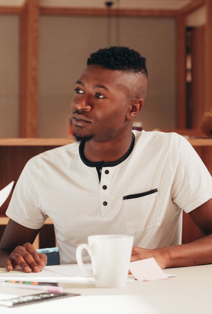 A diverse team of software engineers gathered around a desk, pointing at a screen and discussing code in a peer-review session.
