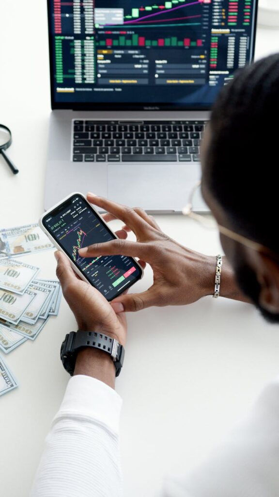 A person with a worried expression looking at a volatile red and green cryptocurrency price chart on a computer monitor.