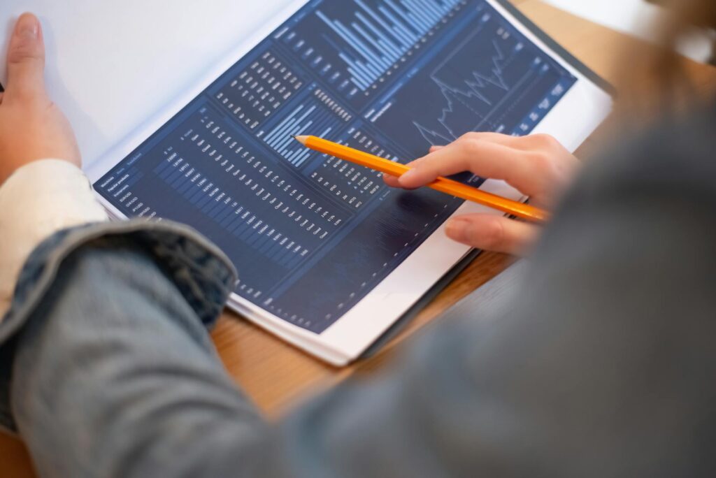 An investor carefully analyzing complex charts and data on multiple computer monitors in a dimly lit room.