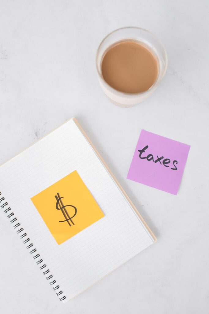 A person's hands writing a crypto exit strategy in a notebook next to a calculator and a coffee mug.