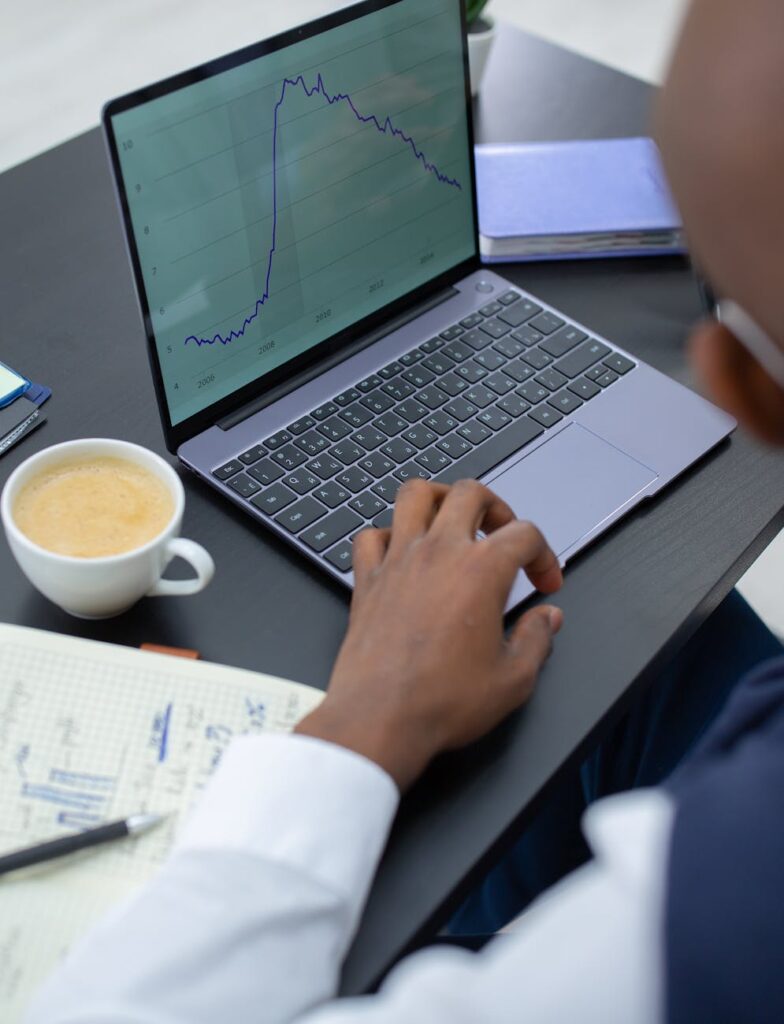 A focused investor looking at complex charts and data on a monitor in a dimly lit room, analyzing cryptocurrency trends.