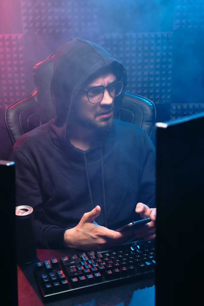 A hooded figure typing code on a laptop, symbolizing digital privacy and security.
