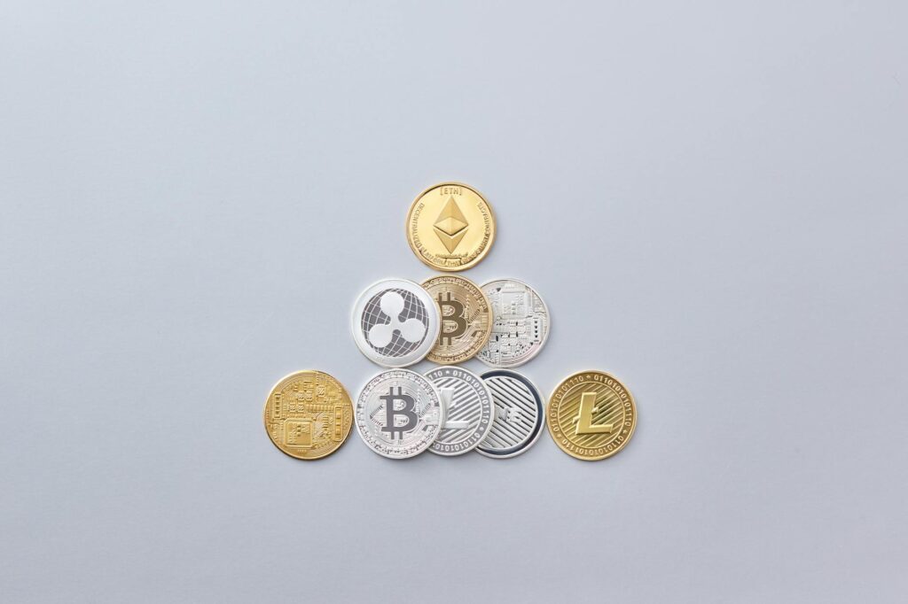 A variety of physical cryptocurrency coins, including Bitcoin and Ethereum, stacked in a pile.