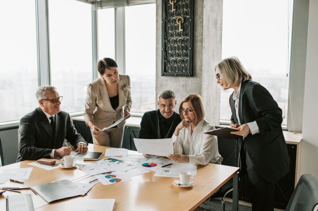 A multi-ethnic group of young professionals pointing at a large monitor displaying complex cryptocurrency market data.