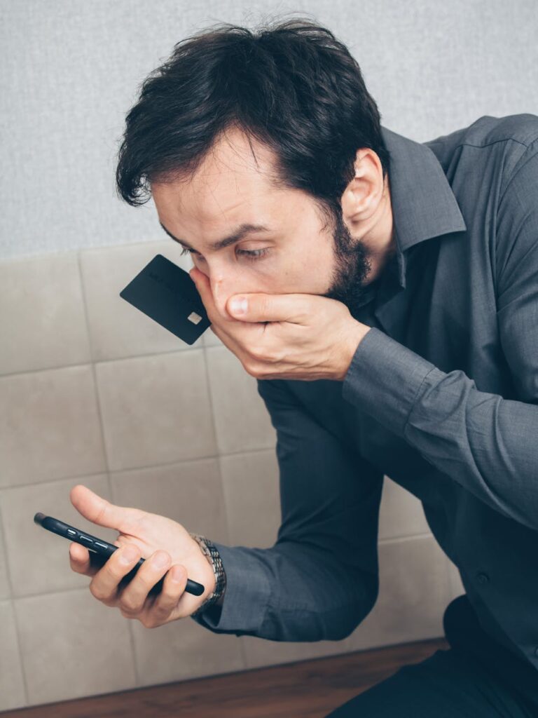 A crypto investor looking concerned at a falling price chart on their smartphone screen.