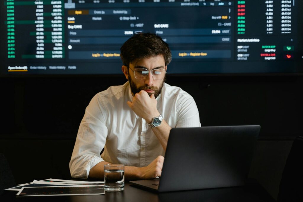 An investor looking concerned while viewing a falling cryptocurrency chart on their laptop, illustrating market volatility.