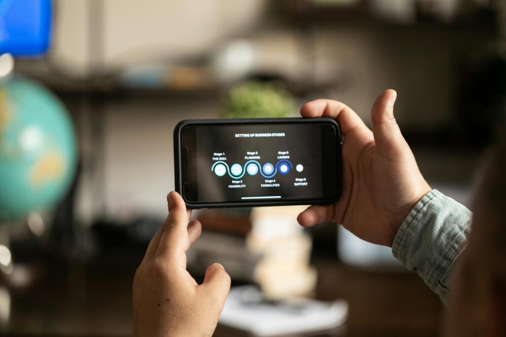A close-up of a person's hand holding a smartphone displaying a volatile cryptocurrency price chart with green and red candlesticks.