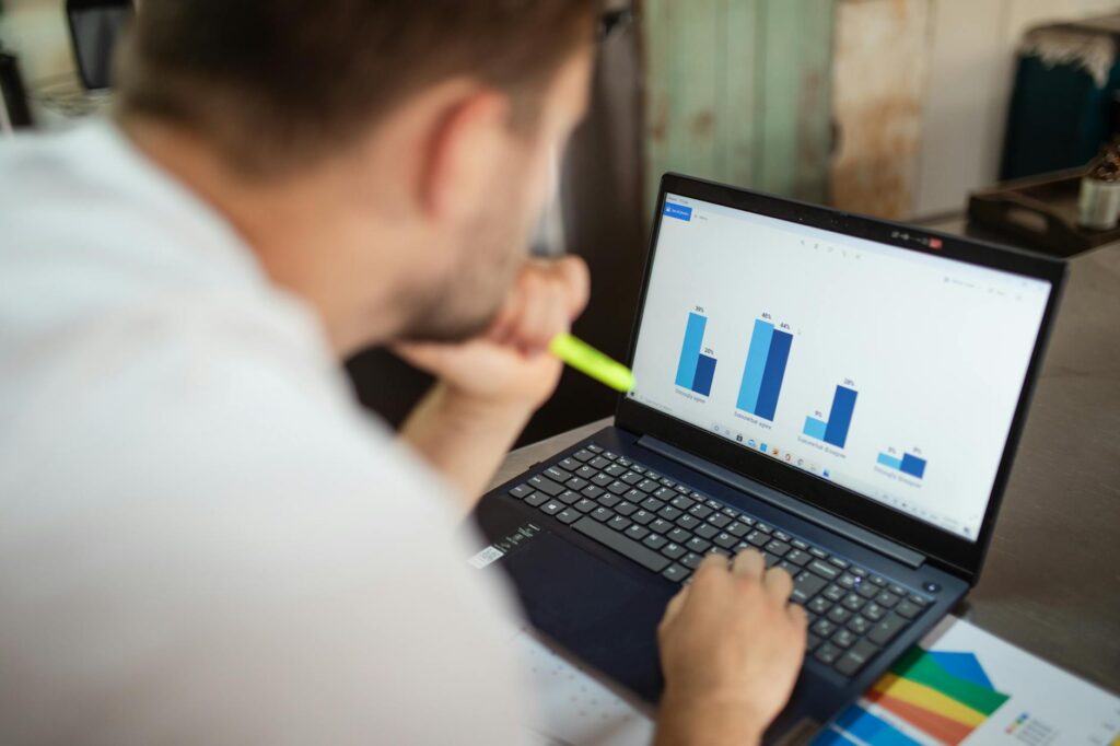 Close-up of a person's hands on a laptop keyboard with a detailed Bitcoin price chart displayed on the screen.