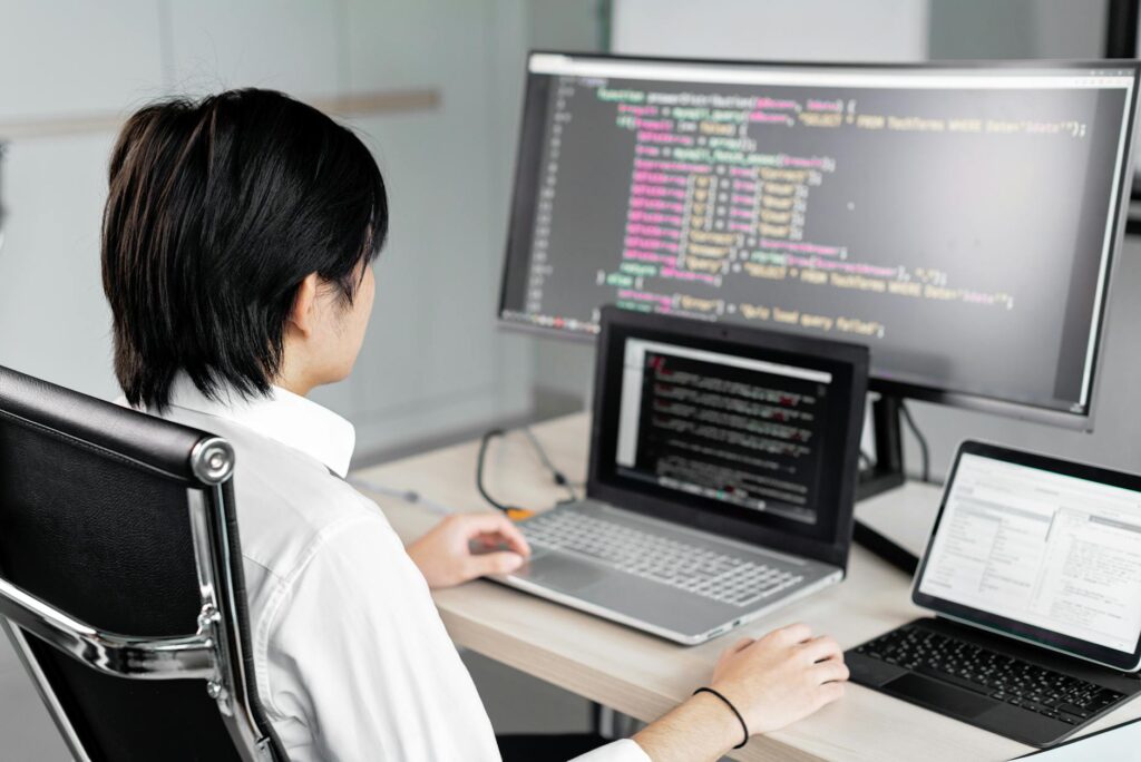 A close-up shot of a software developer's hands typing code for a smart contract on a dark-themed monitor.