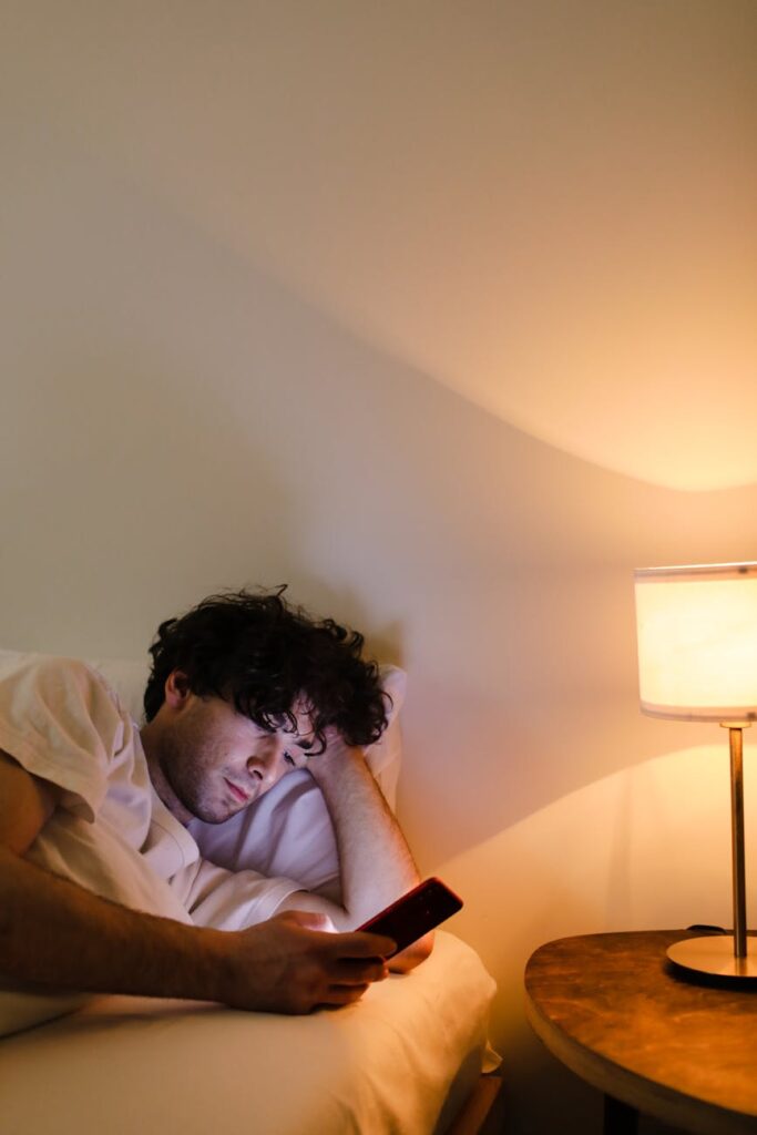 A person looking at a cryptocurrency price chart on their smartphone screen, with a laptop in the background.