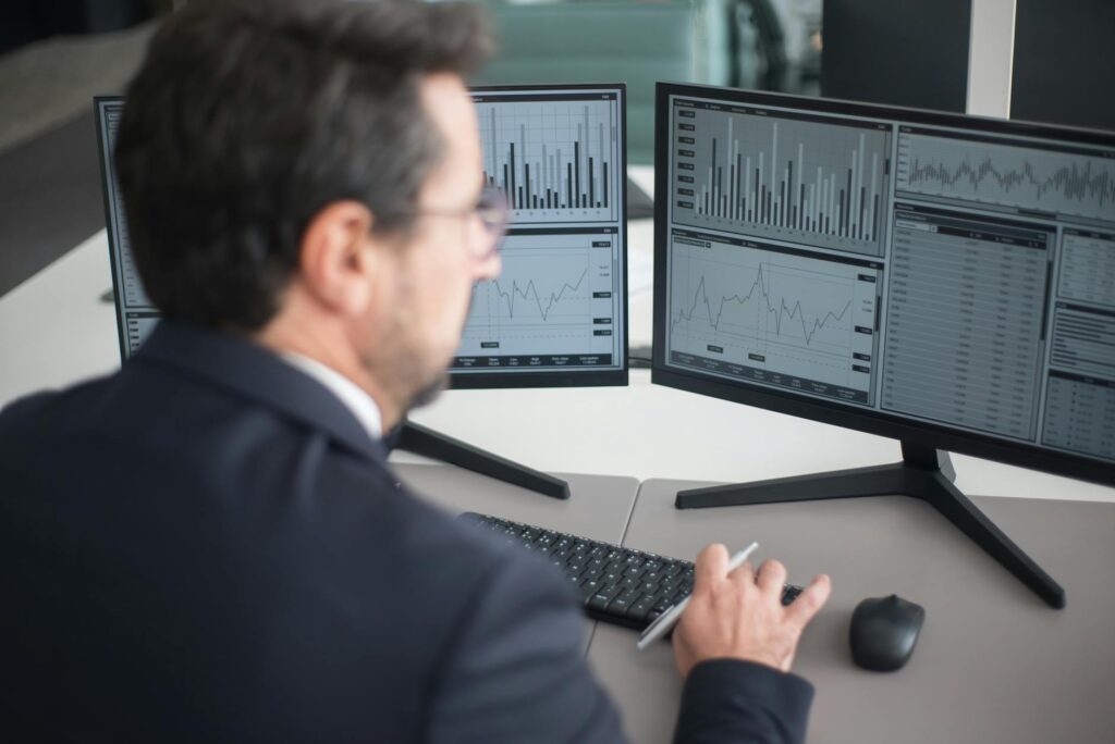 A trader's desk with multiple monitors displaying complex cryptocurrency price charts and order books.