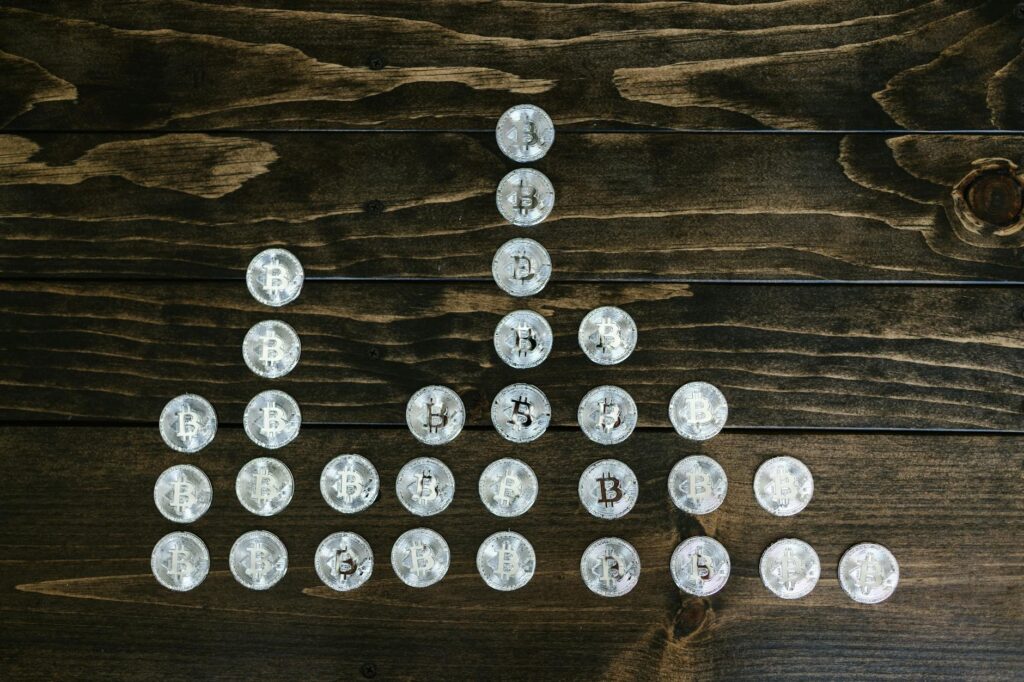 A close-up photograph of a stack of physical Bitcoin, Ethereum, and other altcoins on a dark surface.
