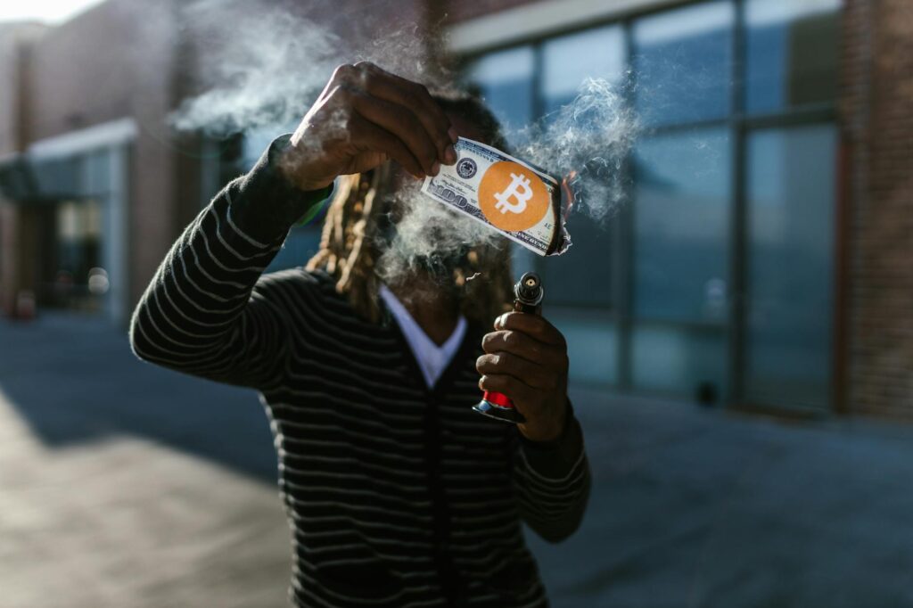 A close-up of a person's hands holding cash from various countries alongside a physical Bitcoin.