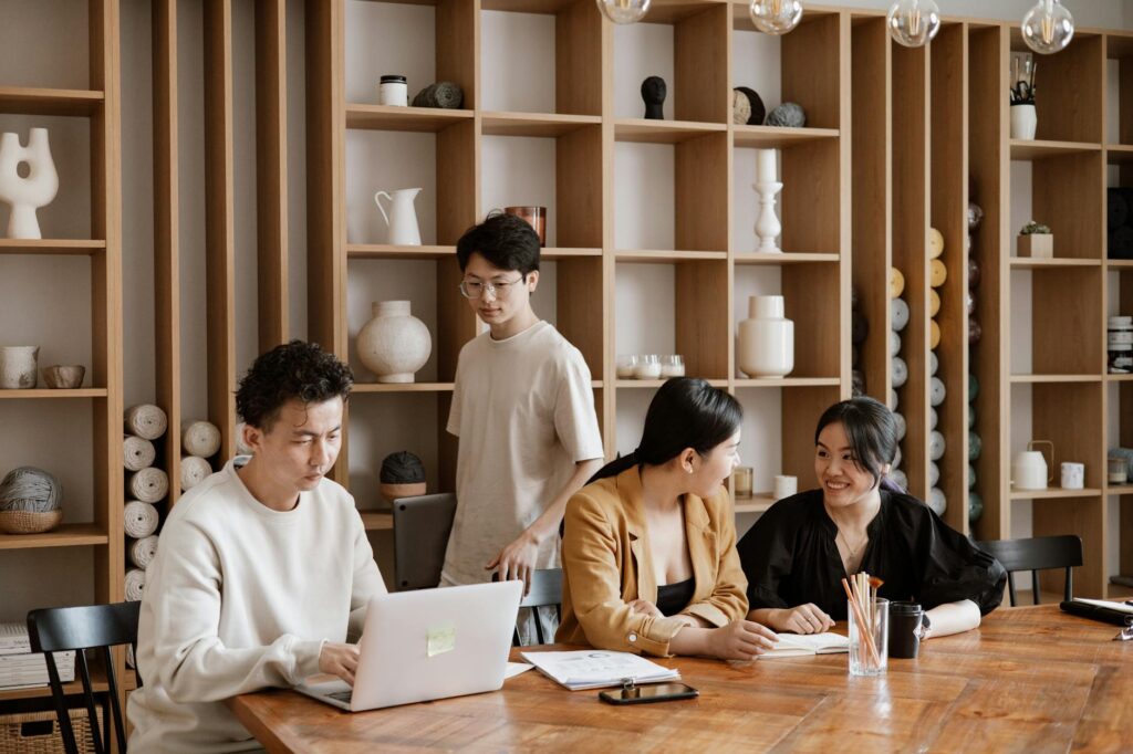 A diverse team of people working together around a table with laptops, representing a DAO's collaborative spirit.