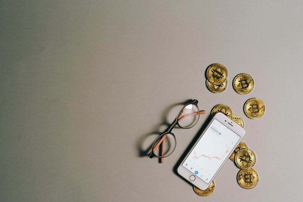A close-up of a person's hand holding a smartphone displaying a colorful cryptocurrency price chart.