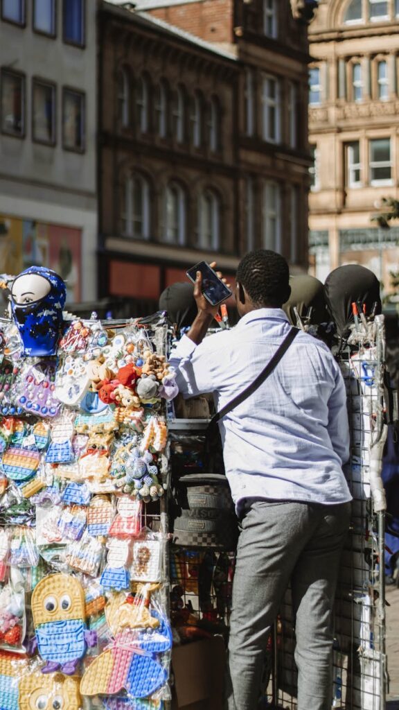 A close-up of a person's hand holding a smartphone displaying a Bitcoin wallet, with a bustling international marketplace in the background.