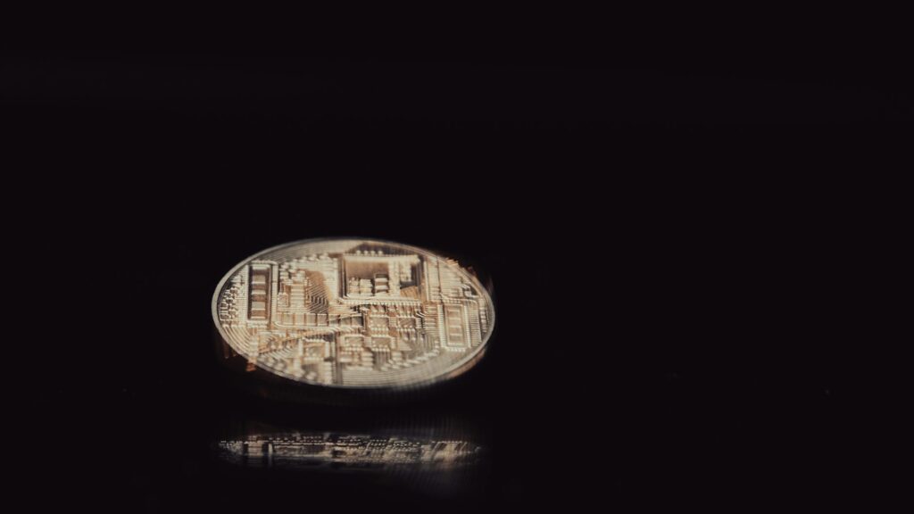 A close-up shot of a physical Bitcoin coin resting on a complex computer motherboard.