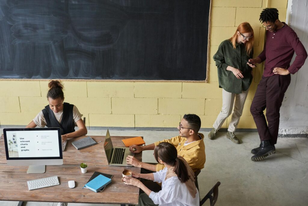 A diverse group of professionals working together around a table with laptops, symbolizing a business using a multi-sig wallet.