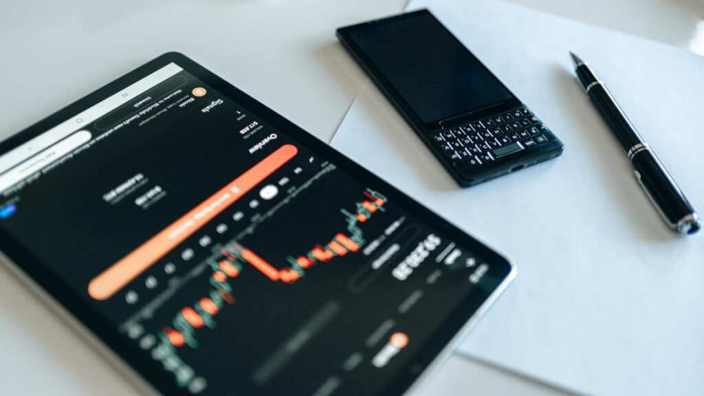 A trader's focused face illuminated by complex cryptocurrency candlestick charts on their laptop.