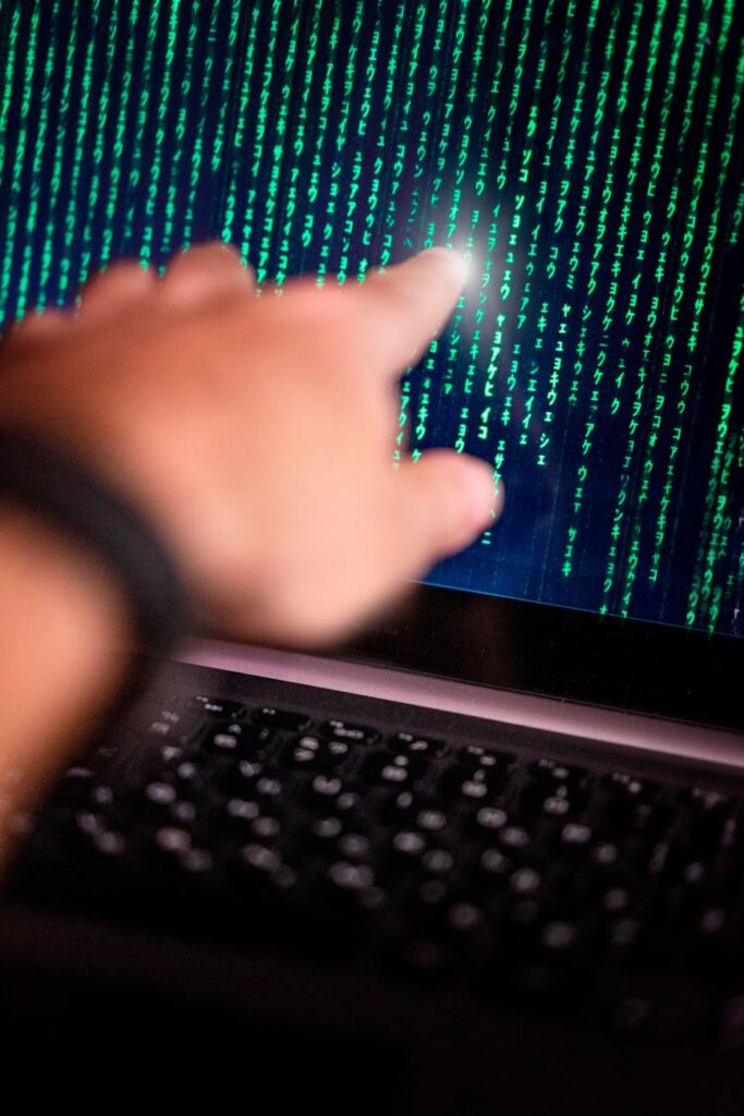 An investor sits in a dimly lit room, looking puzzled at complex stock market and crypto charts on a computer monitor.