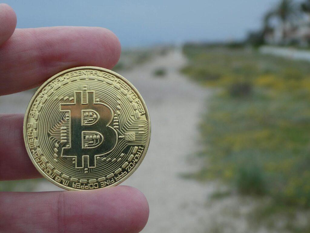 A close-up of a physical gold coin stamped with a Bitcoin logo, symbolizing the tokenization of real-world assets.