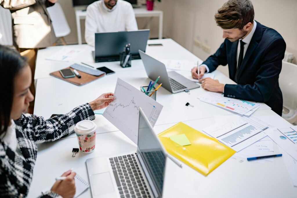 A group of diverse investors collaborating in front of a large screen displaying complex financial data and crypto charts.