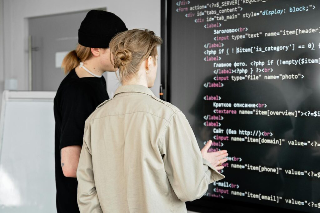 A diverse team of software engineers collaborating around a computer with lines of code visible.